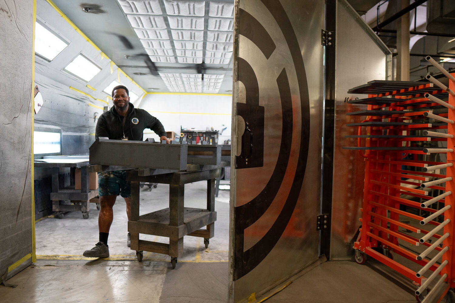 Maker moving work through the spray-booth doorway